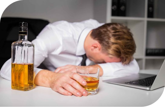 Мужчина лежит на столе с стаканом алкоголя