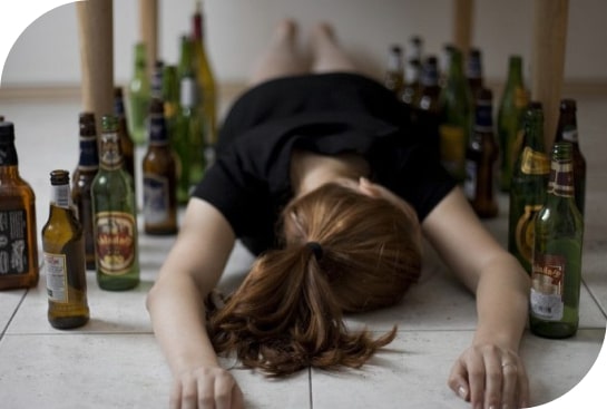 Женщина валяется на полу в окружении бутылок